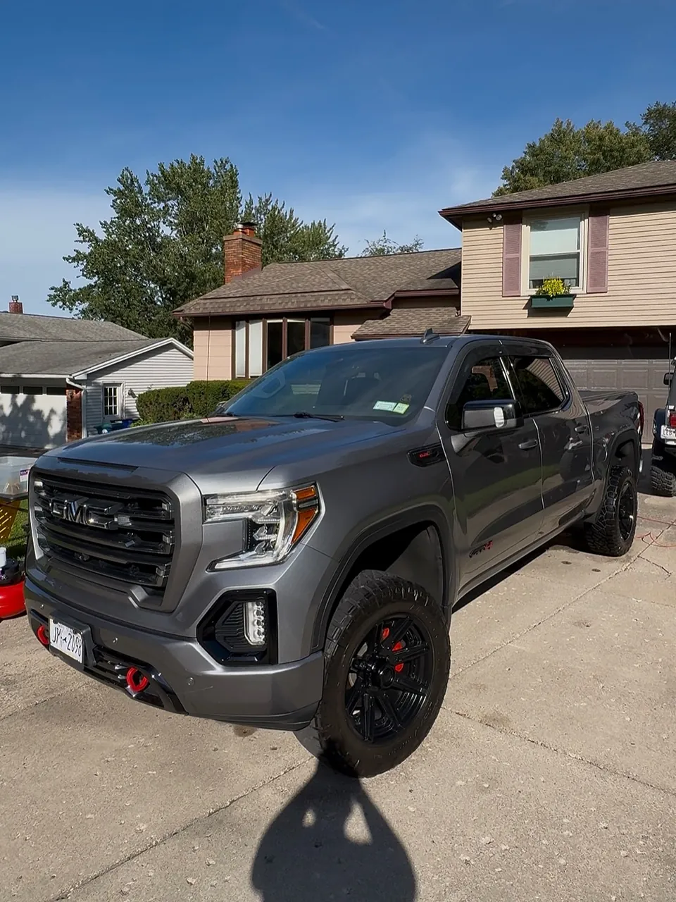 Gray GMC AT4 pickup with black wheels parked in a driveway after a full refresh