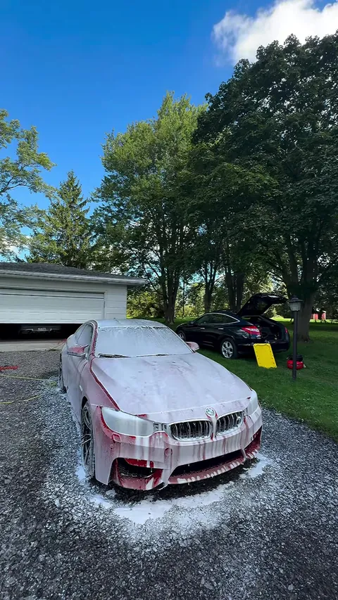 BMW M4 covered in foam on a sunny day