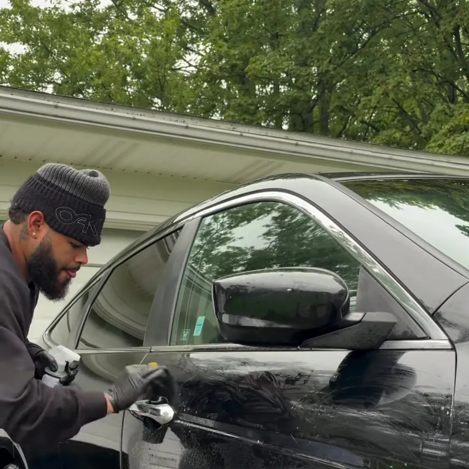 Detailer running a clay bar over the door of the black Crosstour